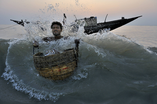 Photo d'un pêcheur avec-panier-pris-dans-une-vague, photo de Xavier Desmier